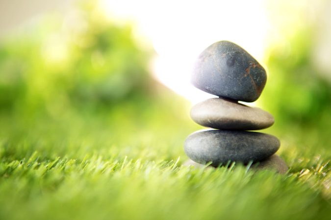 Agencements calmes naturels - pierres zen empilées en équilibre sur herbe verte avec lumière dorée