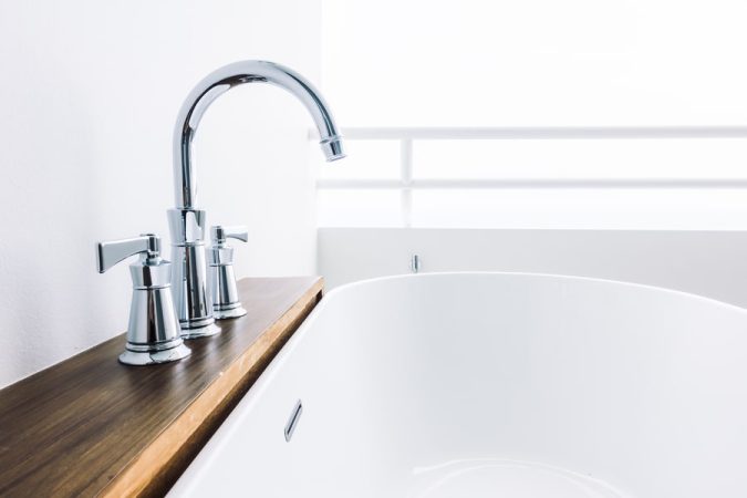 Robinet moderne chromé installé sur baignoire blanche, élément clé de l'installation de plomberie de votre salle de bain
