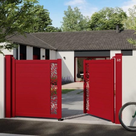 Portail battant en aluminium rouge avec découpes décoratives, ouvert devant une maison moderne.