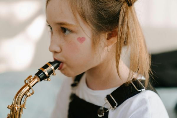 Gros plan sur une jeune fille jouant du saxophone, un excellent instrument à vent pour enfant.