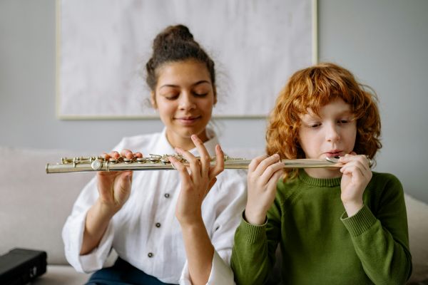 Une jeune femme enseigne la flûte à un enfant, mettant en lumière les instruments à vent pour enfant