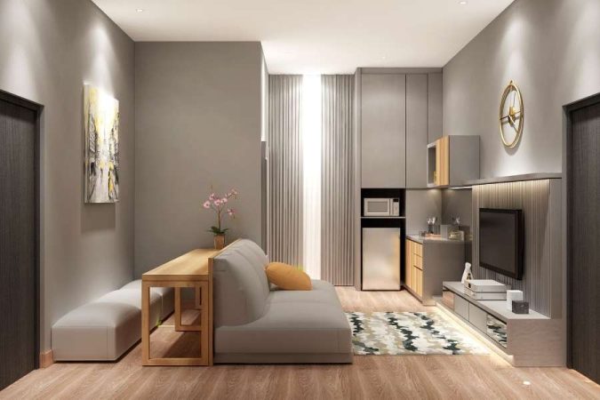 Petit salon moderne avec canapé gris, kitchenette intégrée et décoration minimaliste