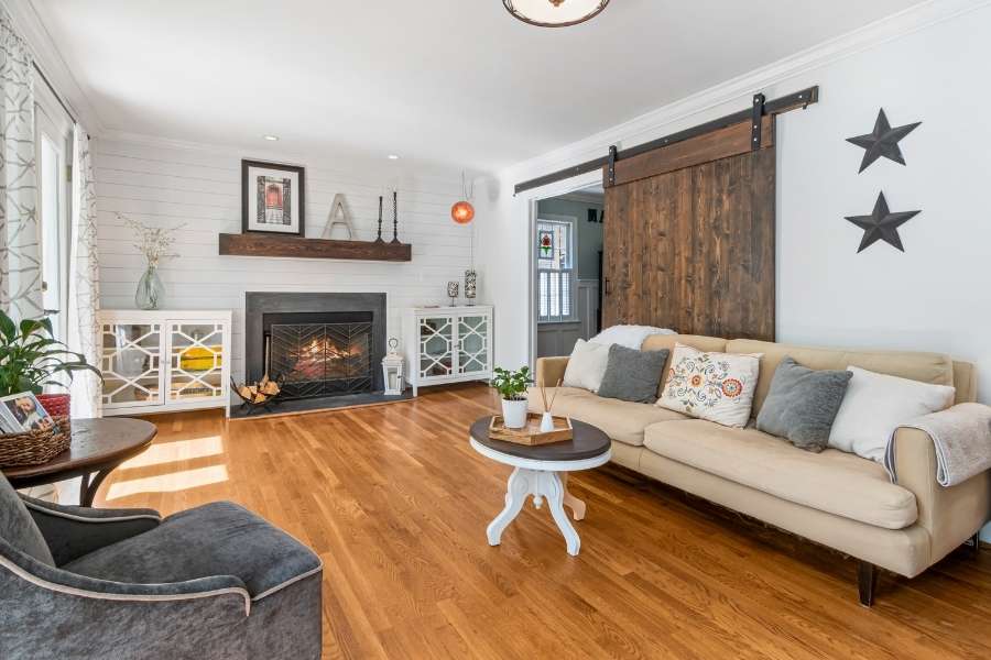 Salon cosy et fonctionnel dans un petit espace de vie Salon chaleureux avec parquet, cheminée, porte coulissante en bois et canapé beige