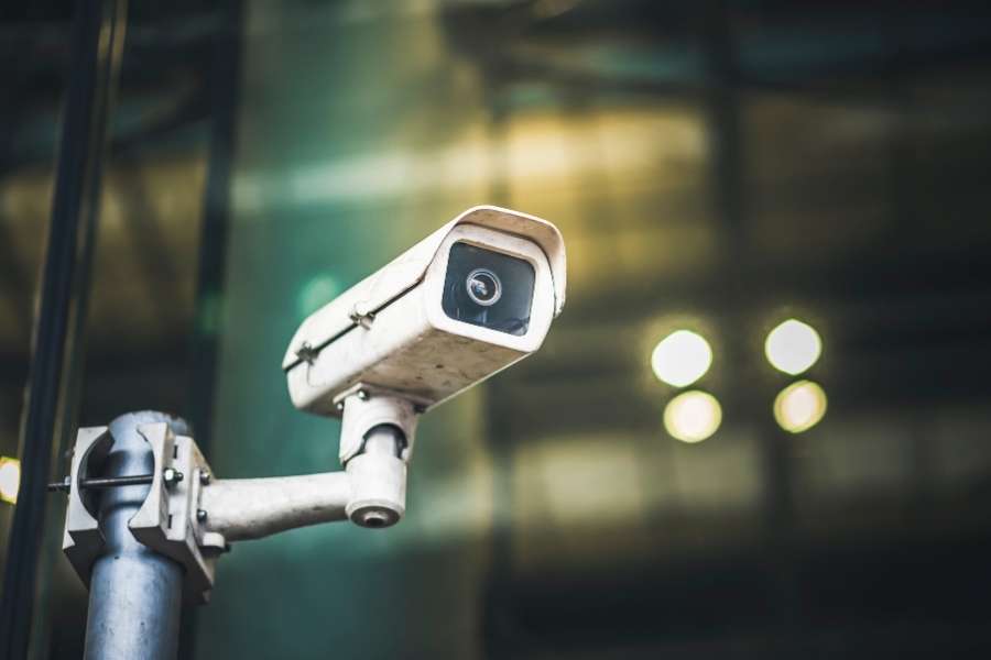 Caméras de surveillance professionnelles pour la sécurité des espaces publics Caméra de surveillance extérieure blanche fixée sur support mural avec fond urbain flou
