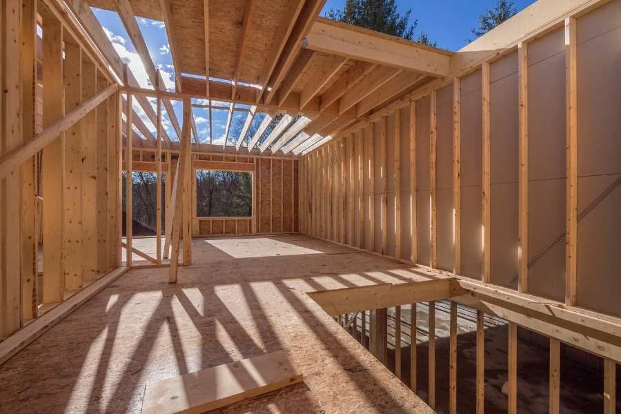 Vue intérieure d’une charpente traditionnelle en bois naturel Intérieur lumineux d'une charpente traditionnelle en bois avec poutres apparentes et ciel bleu