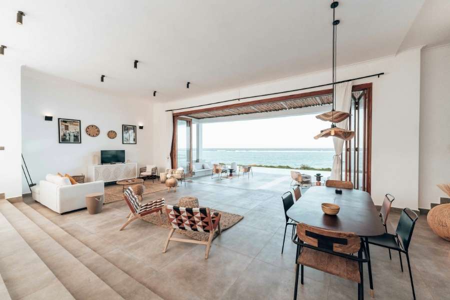 Espace de vie ouvert avec claustra architecturale en bois et pergola Grand salon ouvert avec pergola en bois servant de claustra et vue panoramique sur la mer