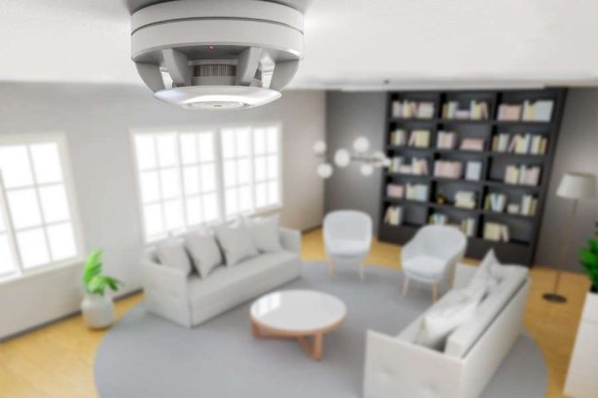 Détecteur de fumée connecté blanc installé au plafond d'un salon contemporain lumineux