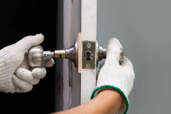 Mains gantées installant une poignée de porte en acier brossé