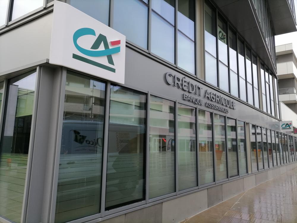 Façade d’une agence bancaire Crédit Agricole. Façade moderne d'une agence du Crédit Agricole avec son logo et l'inscription "Banque Assurances"