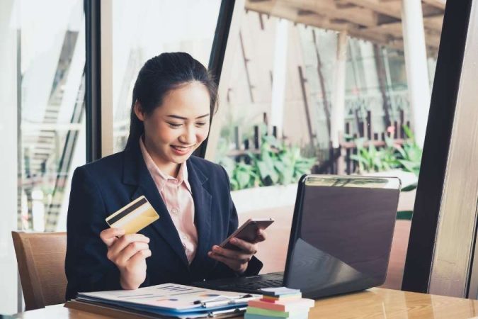 Femme d'affaires vérifiant ses frais bancaires sur smartphone avec carte de crédit