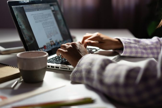 Une personne utilise un ordinateur portable dans la pénombre, illustrant le travail avec des éditeurs de texte.