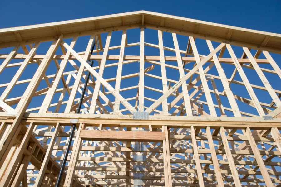 Structure de charpente saine sans signes d’affaissement Charpente en bois neuf avec fermes et chevrons sous un ciel bleu nuageux