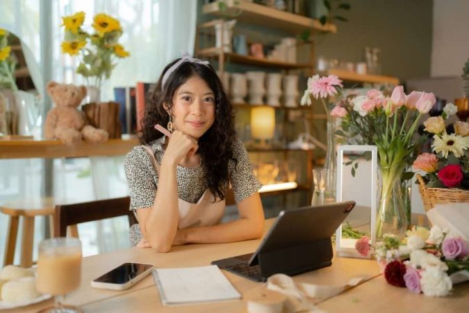Jeune femme autoentrepreneur travaillant sur tablette dans son atelier de fleuriste