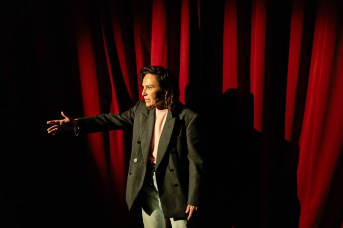 Une actrice répète sur scène, rideaux rouges en arrière-plan, illustrant l'ambiance des cours de théâtre à Paris