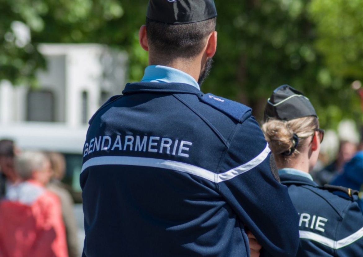 Deux gendarmes français, vus de dos, portant l'uniforme bleu marine avec l'inscription "GENDARMERIE".
