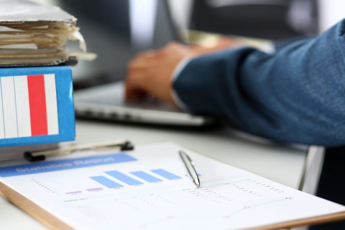 Gros plan sur un rapport de statistiques et des dossiers de bureau, symbolisant l'étude des chiffres de l’économie française