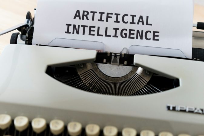 Une machine à écrire vintage contenant une feuille de papier où est inscrit "ARTIFICIAL INTELLIGENCE", idéale pour découvrir les nouveaux modèles d'IA pour bien débuter cette année.