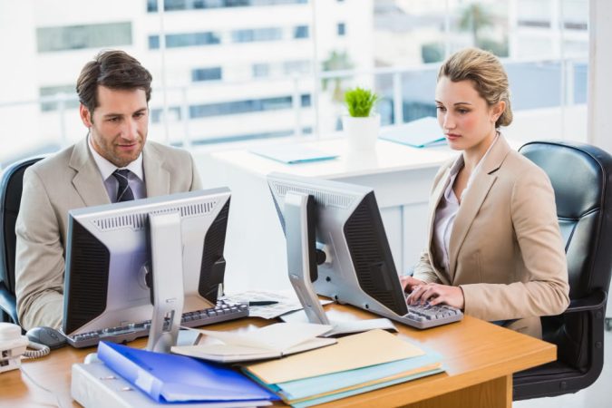 Deux collaborateurs dans un bureau lumineux effectuent des démarches professionnelles sur la plateforme MonIdenum fr Kbis
