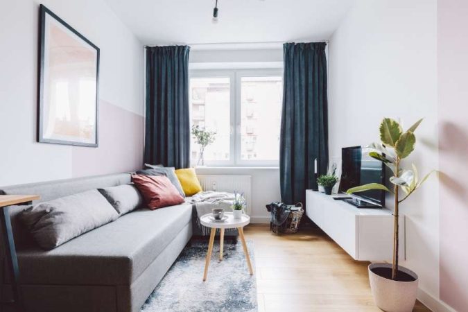 Un petit salon moderne et lumineux avec un canapé gris et une table basse en bois.