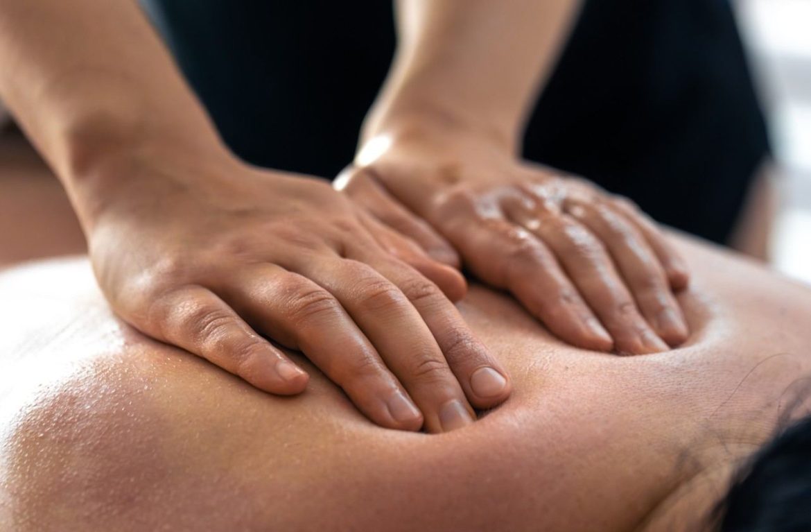 Les mains d'un massothérapeute exécutent un massage suédois pour soulager les tensions musculaires du dos.