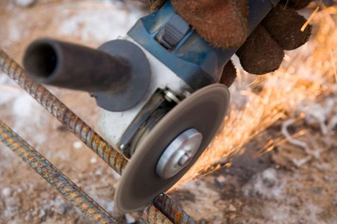 Utilisation d'une meuleuse pour une découpe de fer sur mesure sur un chantier.