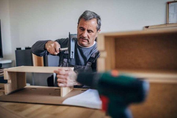 Un menuisier expérimenté assemble une structure en bois clair pour fabriquer sa table.